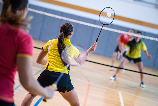Zwei Mädchen spielen gegen zwei Jungs Badminton.