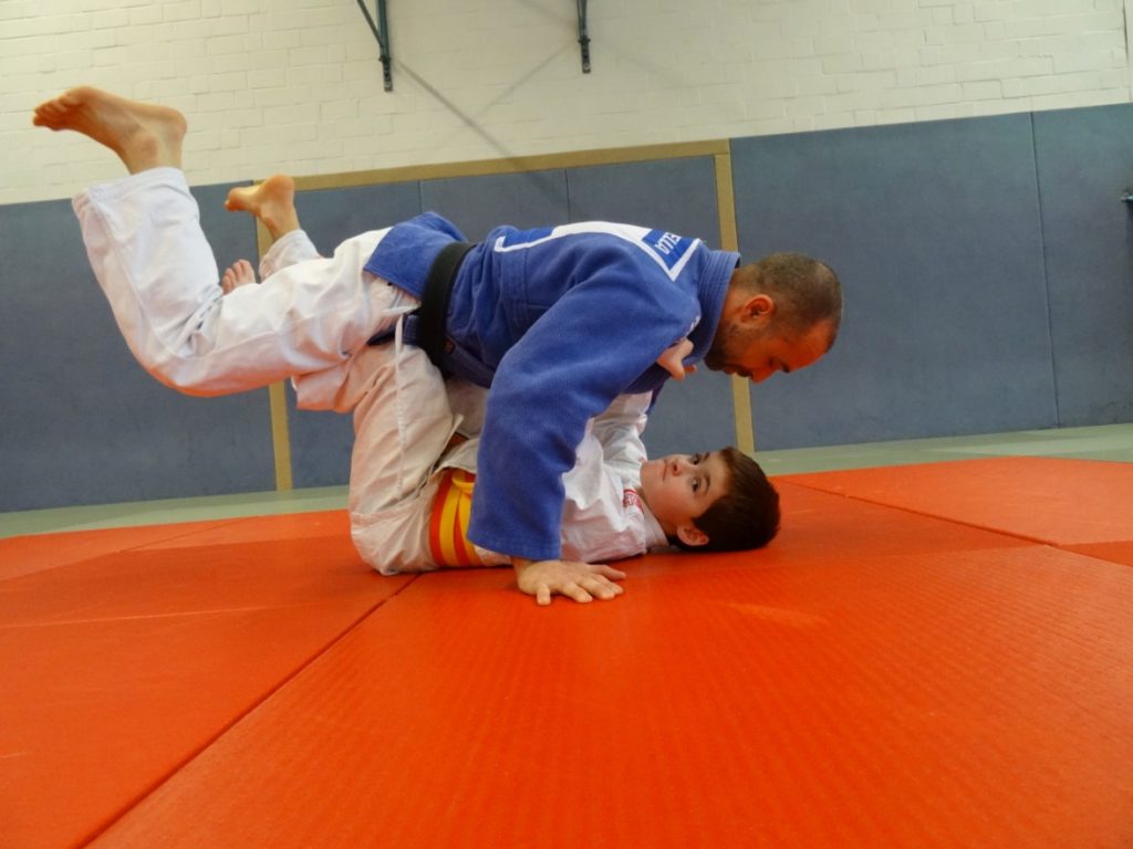 Kind hält einen Mann in der Luft während des Judo-Unterrichts.
