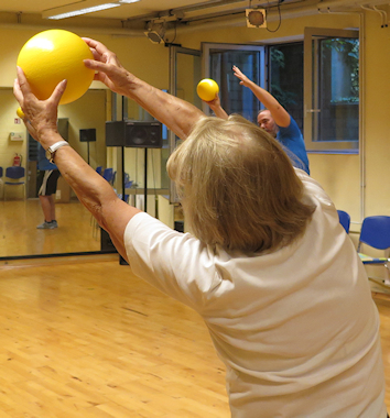 Seniorin macht Sport mit einem Ball.