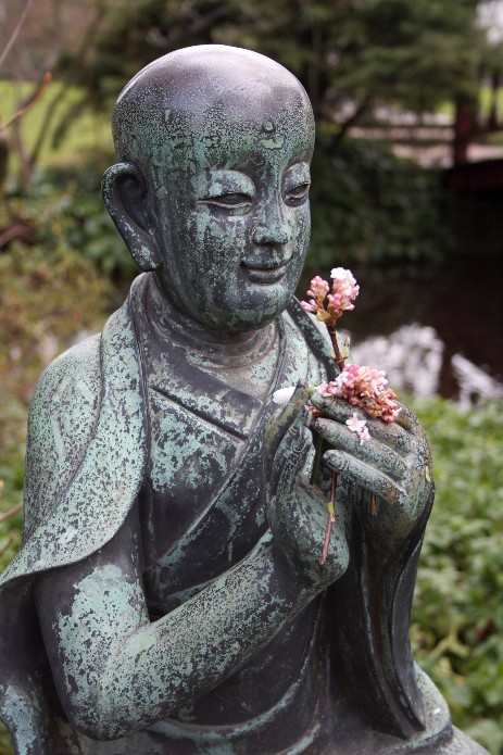 Statue mit pinken Blumen in den Händen.