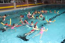 Eine Gruppe Kinder schwimmen mit Hilfe von Schwimmnudeln.